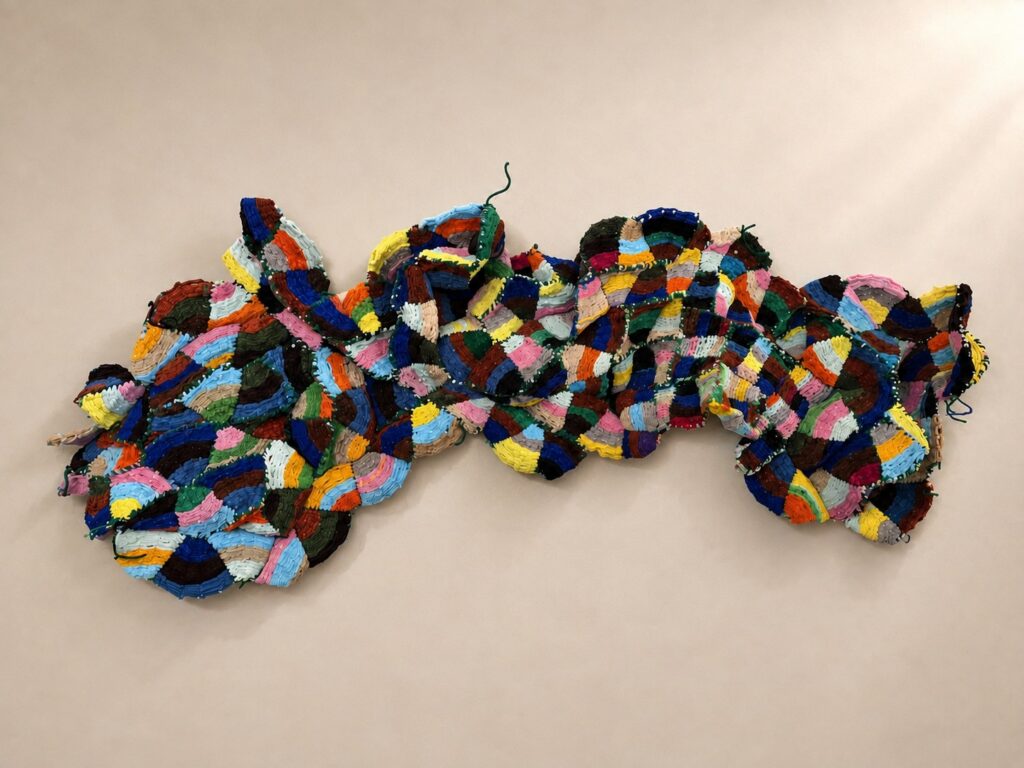 Long wall piece of multicolor patchwork discs. Pipe cleaner sculpture by Ted Fullwood