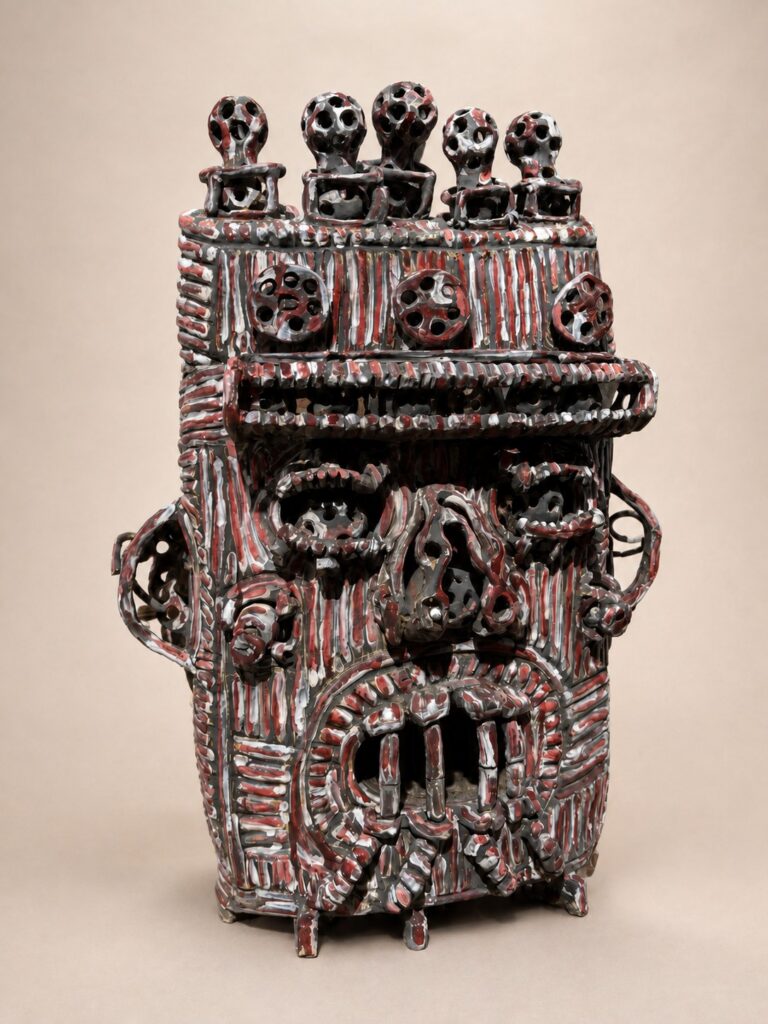 Maroon box head crowned with small figures. Ceramic sculpture by Ted Fullwood