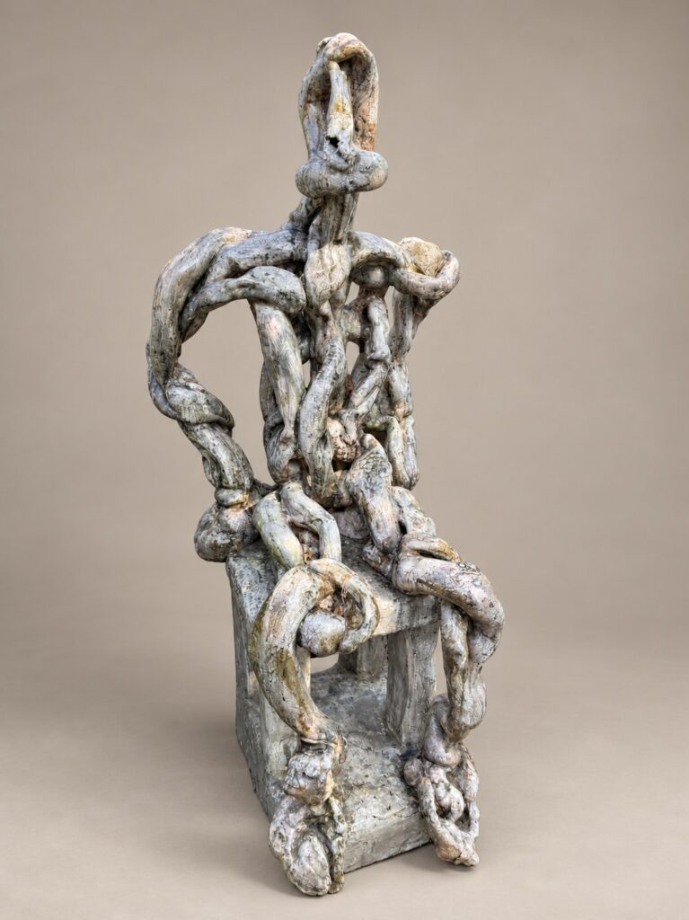White chain-link figure on a chair. Ceramic sculpture by Ted Fullwood