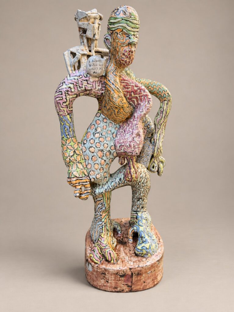 Patterned standing figure with a small figure on its shoulder. Ceramic sculpture by Ted Fullwood